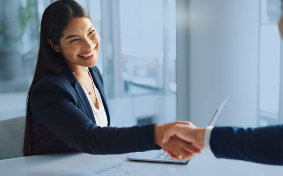 Female lease administrator smiles proudly while shaking hands with someone out of frame.