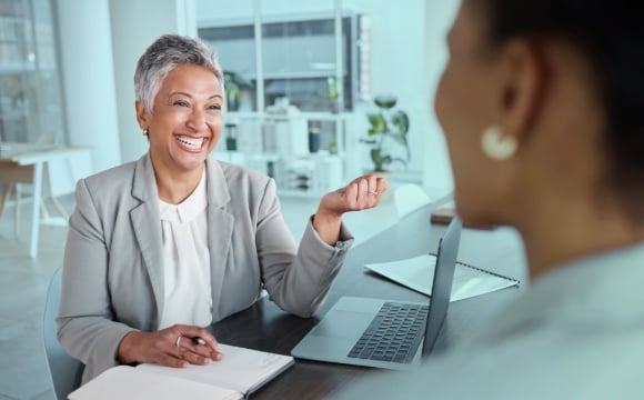 Senior Lease Accountant smiling at a colleague in her office sitting at her desk