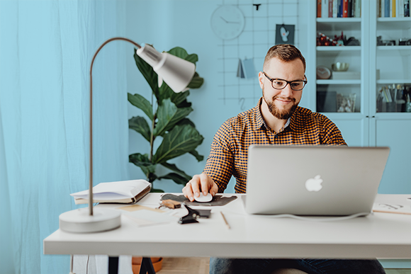 Lease accountant in a modern office looking at his laptop smiling